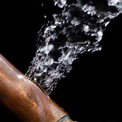 A bursting copper pipe in Southport, with water gushing out.